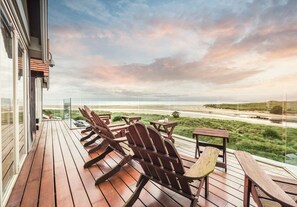 Une terrasse en bois avec des sièges extérieurs et vue sur la plage.