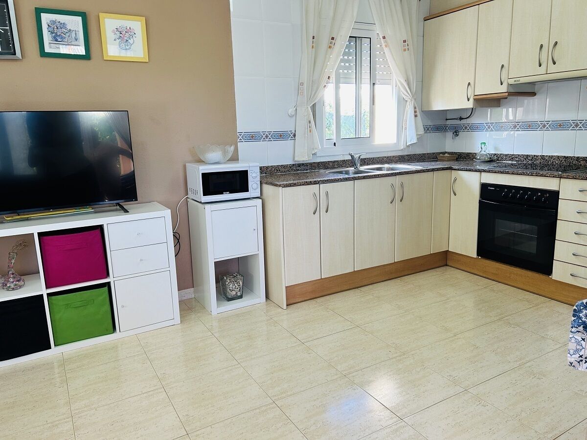 Eine Küche mit weißen Schränken, einer Mikrowelle, einem Spülbecken und einem Herd.