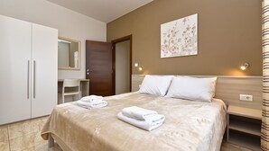 Ein Schlafzimmer mit Bett, Schreibtisch, Stuhl, Kleiderschrank und einer Tür.