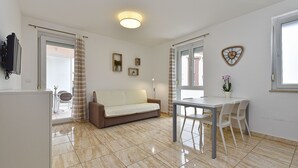 A modern living room with a sofa, a dining table with chairs, and a kitchen area.