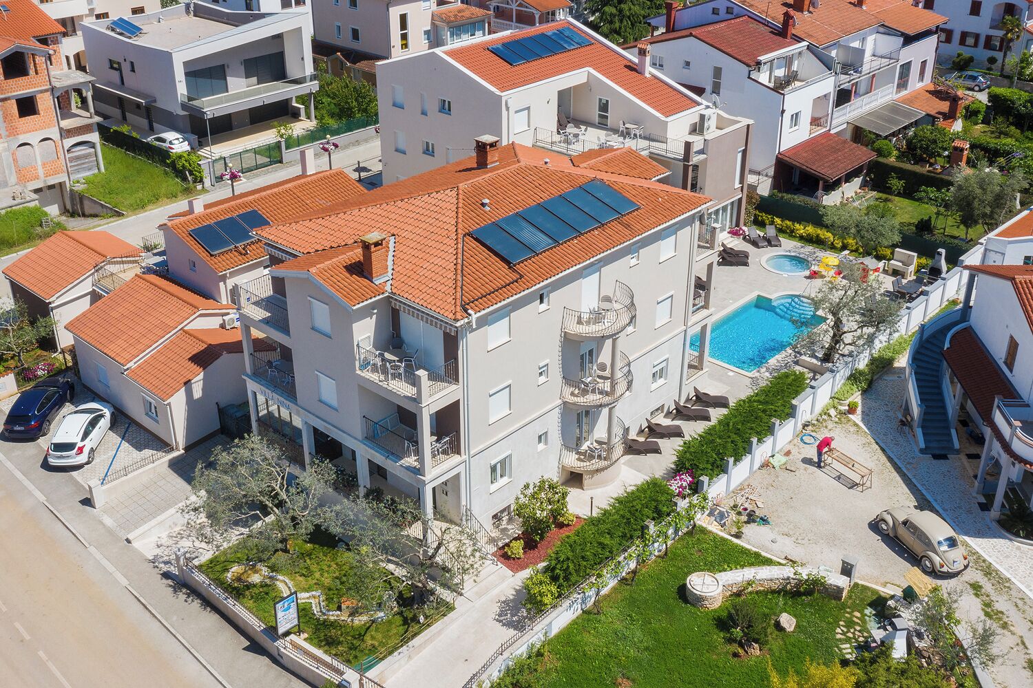 A multi-story residential building with balconies, a swimming pool, and solar panels on the roof.