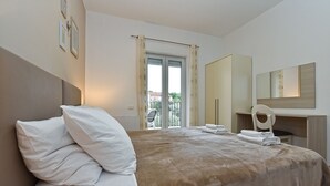 A hotel bedroom with a bed, a chair, a mirror, and a view of the outside. - Apartment 2301/81954 (Istria - Fažana), 250m from the beach (Fažana)
