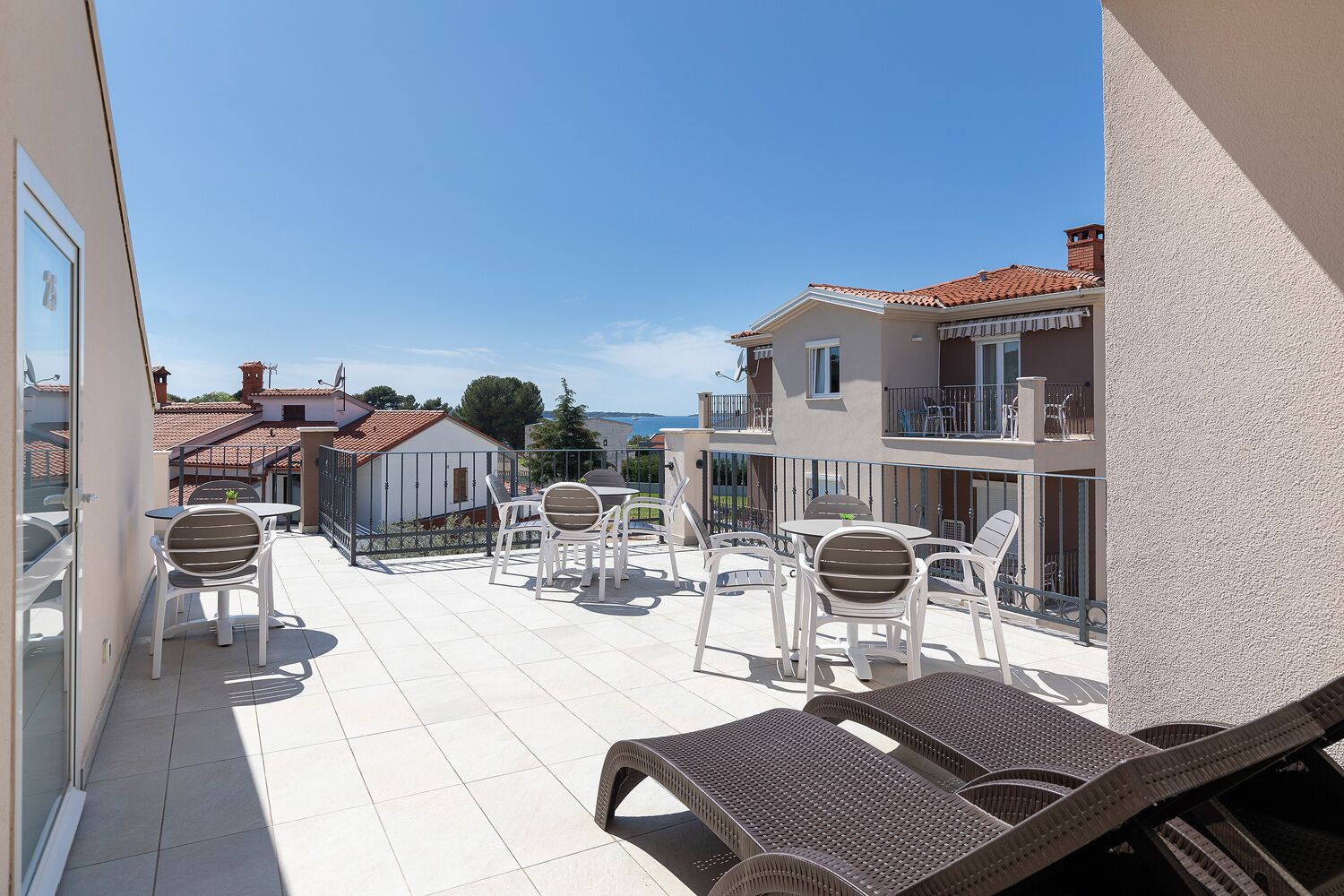 Un balcon avec des meubles d’extérieur, une vue sur la mer et un bâtiment doté d’un toit en tuiles.