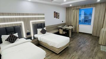 Habitación de hotel con dos camas, un escritorio y una ventana con cortinas.