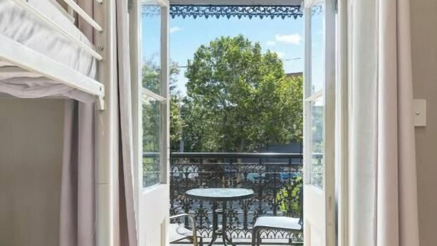 A room with a bed, a window, and a view of an outdoor patio with a table and chairs. - Azzurro Boutique Hotel - Surry Hills (Darlinghurst)