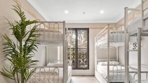 A dormitory room with bunk beds, a potted plant, and a window with a view of trees. - Azzurro Boutique Hotel - Surry Hills (Darlinghurst)