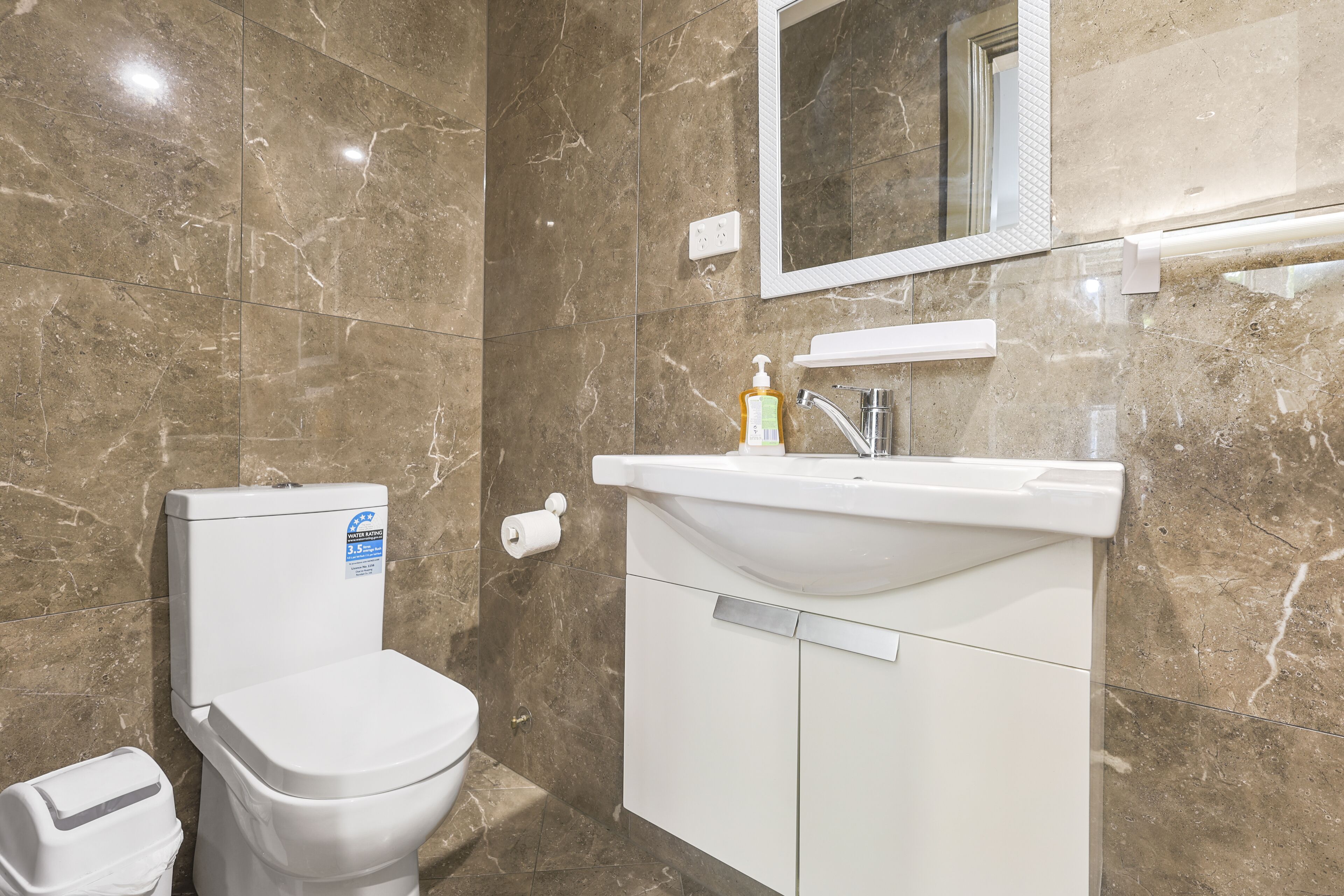 A bathroom with a toilet, sink, and mirror.