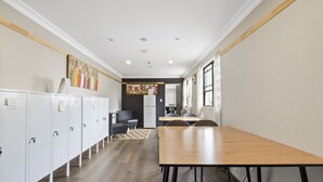 A modern kitchen with white cabinets, a wooden countertop, and a view into the dining area. - Azzurro Boutique Hotel - Surry Hills (Darlinghurst)
