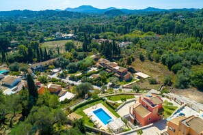Vista aérea de uma área residencial com casas, piscina e vegetação ao redor.