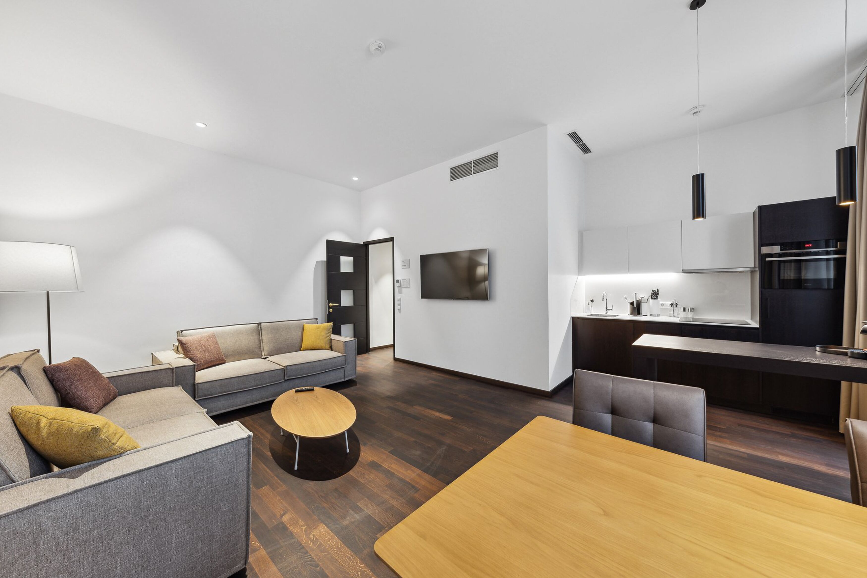A modern living room with a sofa, a coffee table, and a dining area with a wooden table.