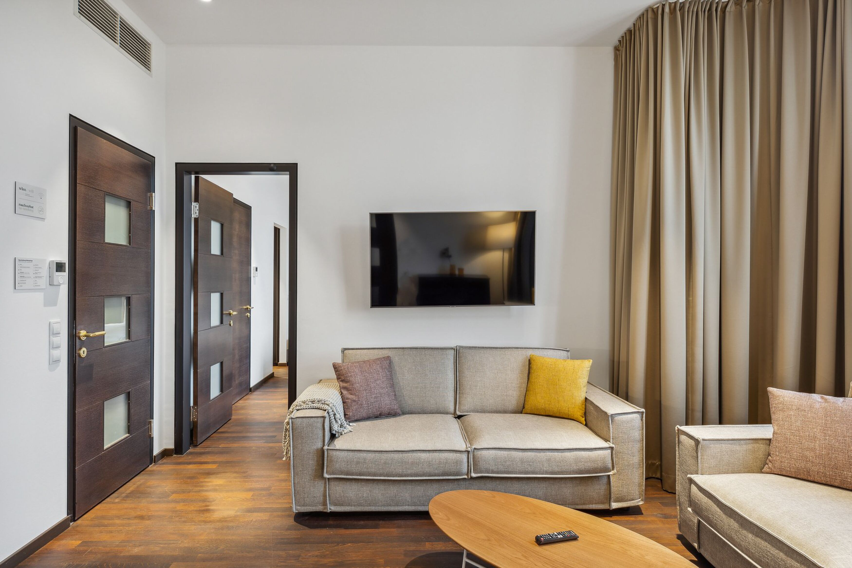 A modern living room with a sofa, a coffee table, and a TV mounted on the wall.