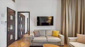 A modern living room with a sofa, a coffee table, and a TV mounted on the wall.