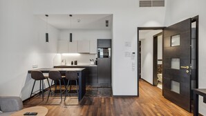 A modern kitchen with a central island, bar stools, and a dining table. - Limehome Vienna Roßauer Lände (Vienna)