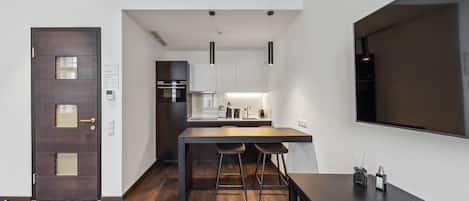 A modern kitchen with a dark wooden table, two bar stools, and pendant lighting.