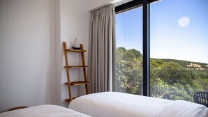 A bedroom with two beds, a wooden ladder, and a view of a green landscape through a large window. - Villa Blauw with Infinity Pool  (LEFKADA)