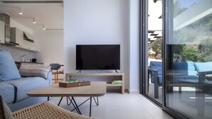 A modern living room with a sofa, a coffee table, a TV, and a balcony with outdoor furniture. - Villa Blauw with Infinity Pool  (LEFKADA)