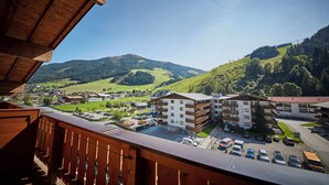 A view of a mountain town with a mix of residential and commercial buildings, a parking area, and a ski lift in the background. - Hotel Forellenhof (Saalbach-Hinterglemm)