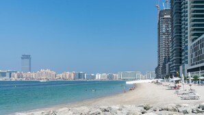 A beach with a city skyline in the background, featuring high-rise buildings and a clear sky.