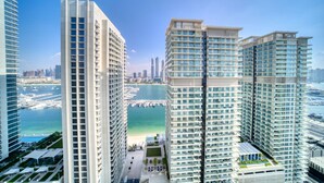 A high-rise building with multiple floors, large windows, and a view of a marina with boats.