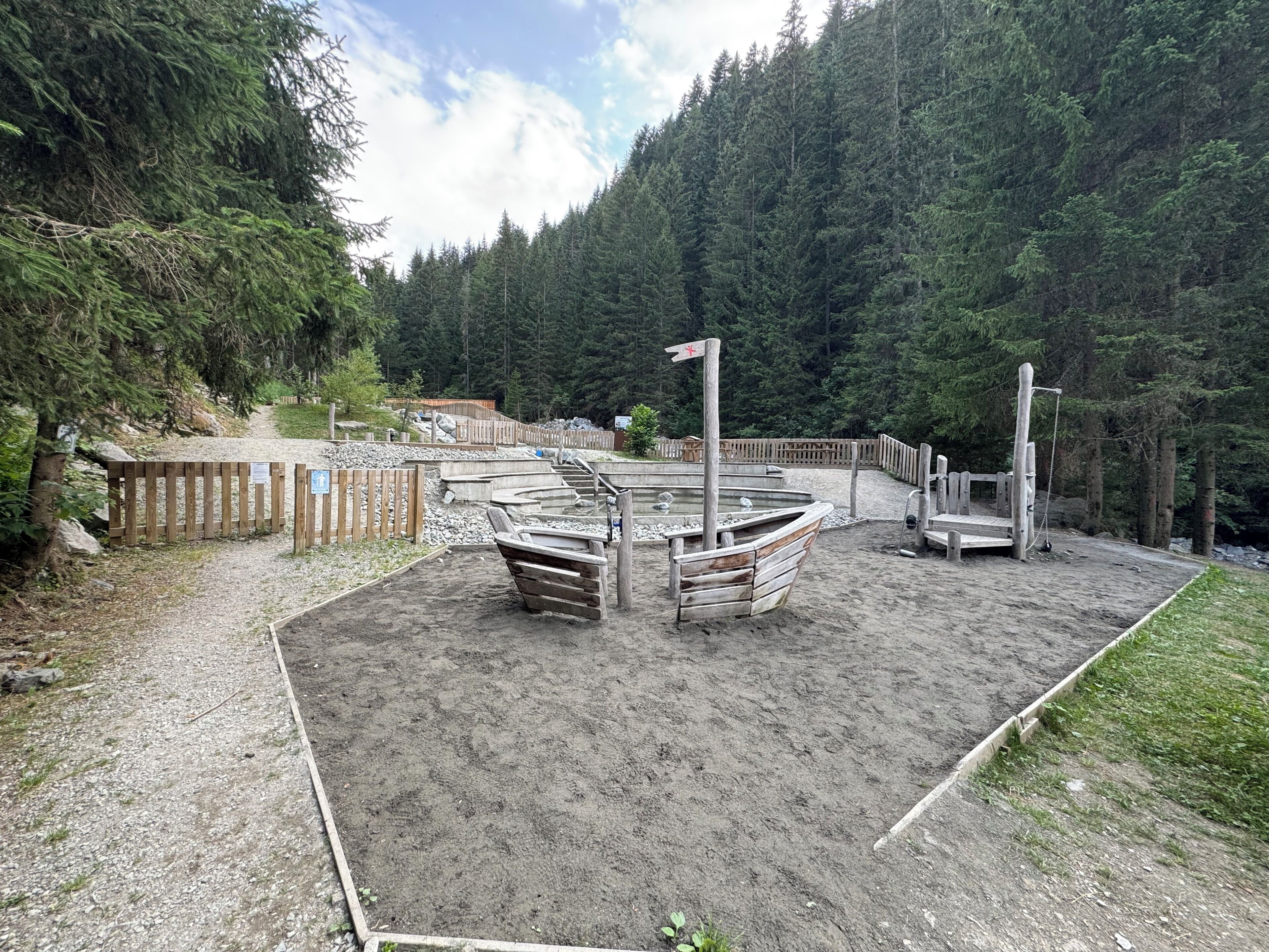 Une zone de plage sablonneuse avec des bancs en bois et un mât pour drapeau.