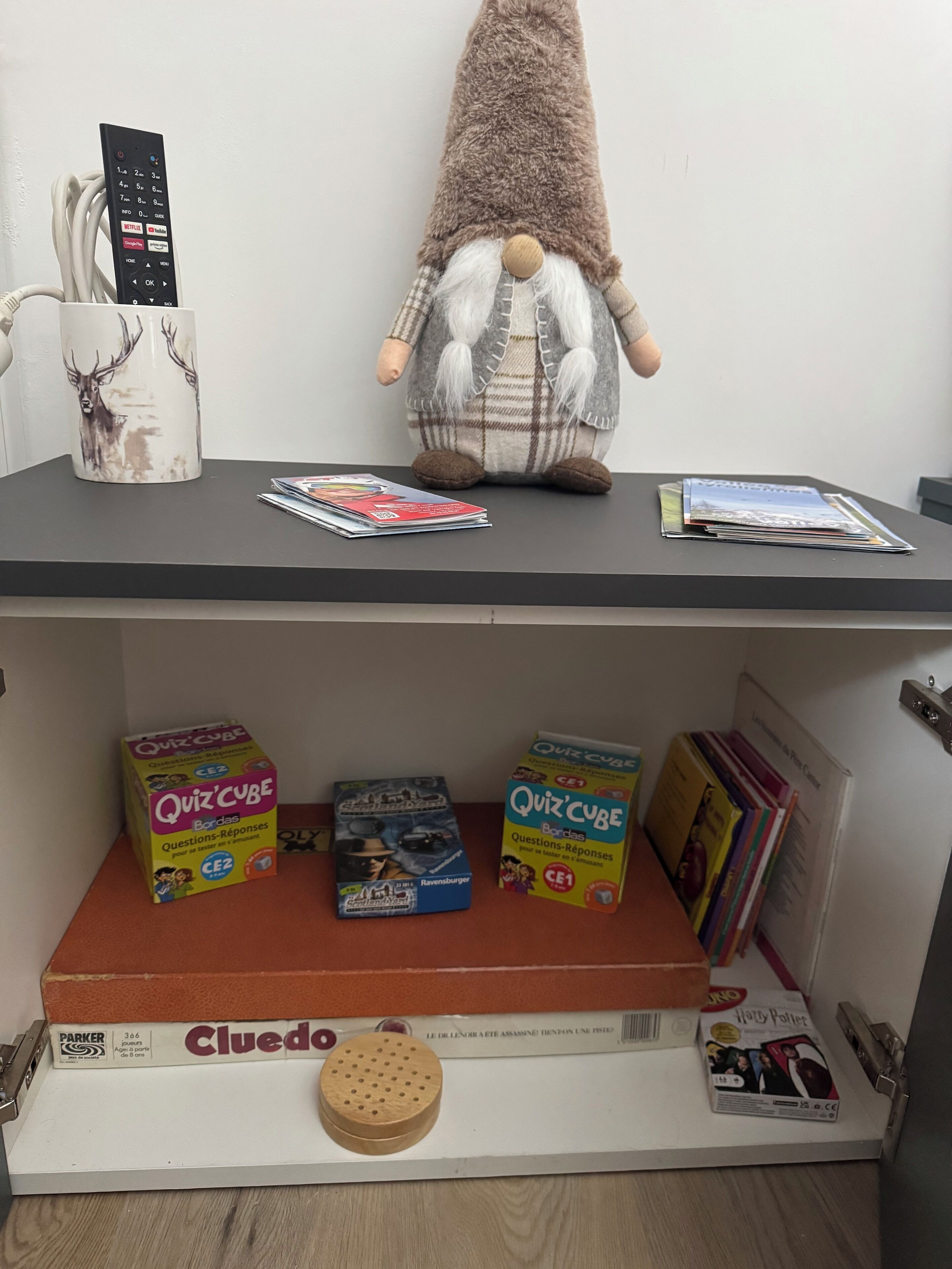 Une étagère avec une figurine de gnome, une télécommande et des livres.