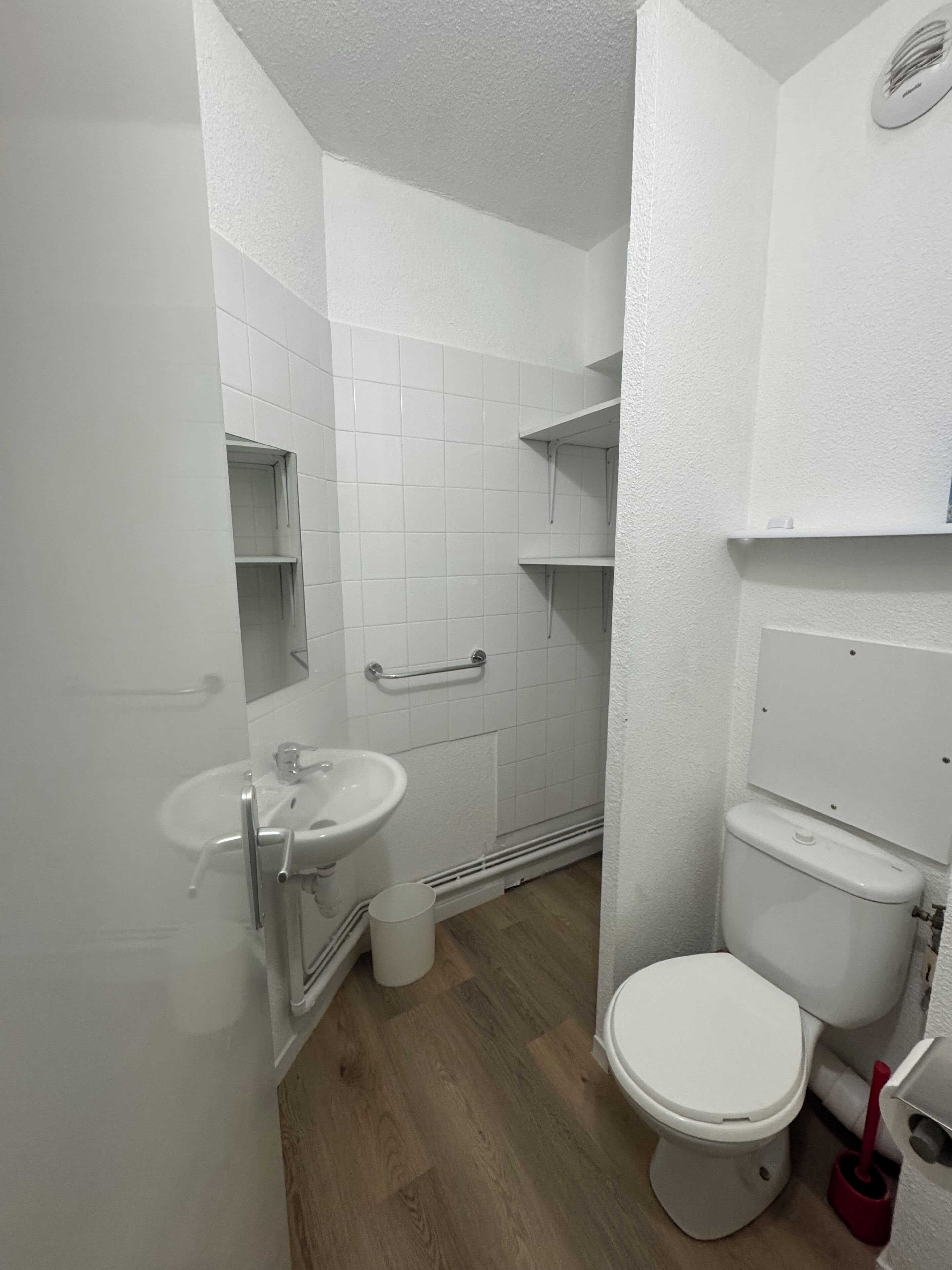 A small, white bathroom with a sink, toilet, and a mirror.