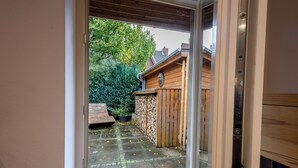 A view through a door into a courtyard with a wooden fence, potted plants, and a stone pathway. - Exklusives Tiny House in Elbnähe (Buxtehude)