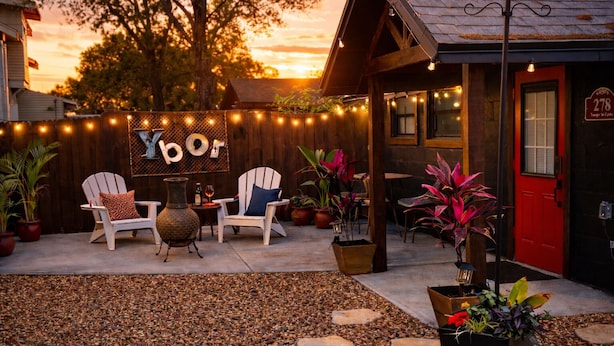 A patio area with outdoor seating, string lights, and a red door.