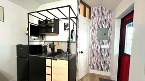 A compact kitchen with a black countertop, a built-in sink, and a small refrigerator.