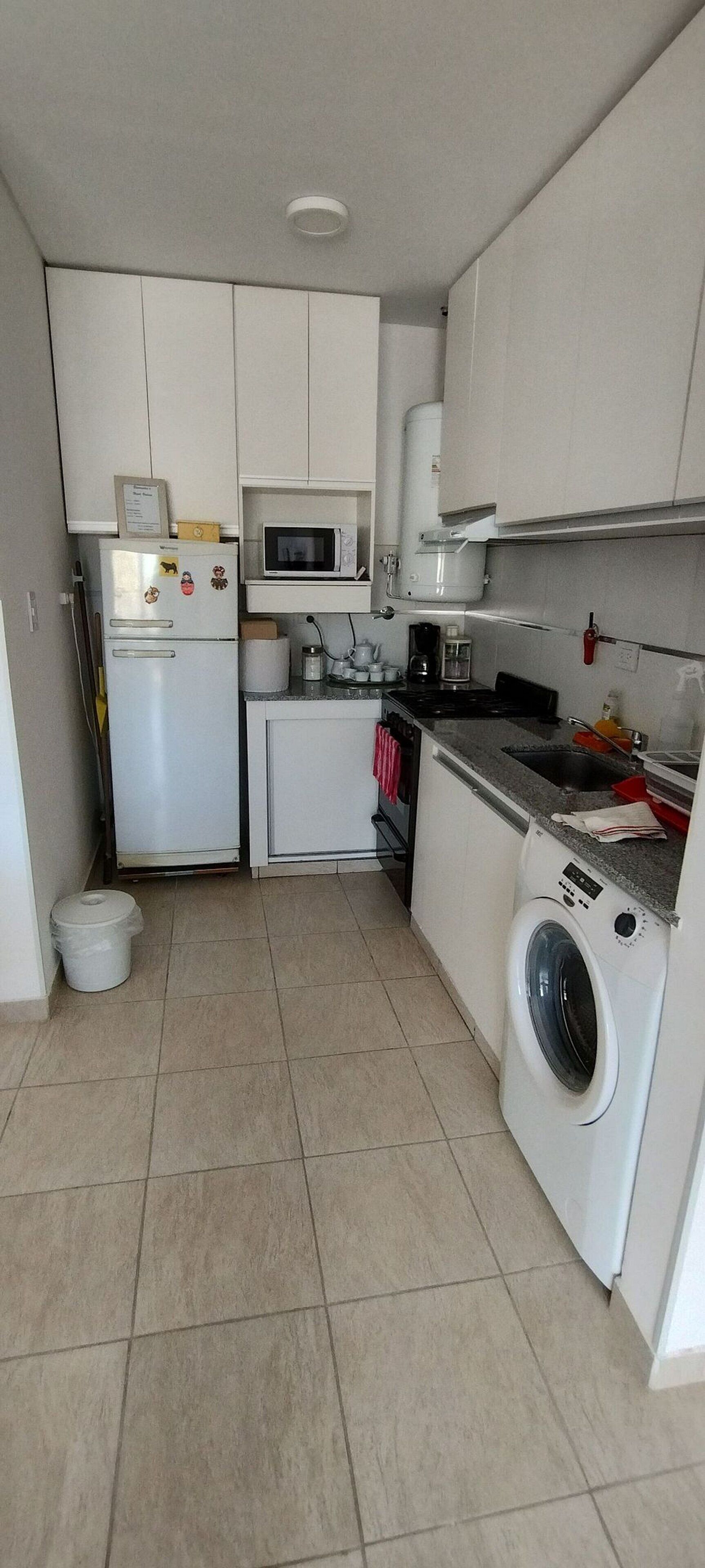 Cuina pràctica amb rentadora integrada, microones i un rentaplat.