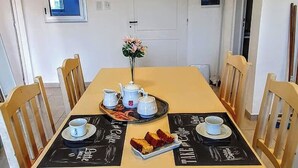 Un coin repas avec une table dressée pour deux personnes, comprenant des théières, des tasses et un plateau avec du pain.