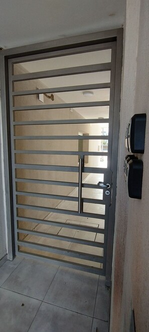 A metal gate with horizontal bars, a door handle, and a keyhole. - Heart Depatamentos (Viedma)