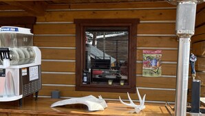 A wooden exterior with a beverage dispenser, a window with a view of a building, and a decorative lantern.
