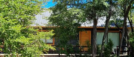 A rustic cabin with a wooden exterior, a covered porch, and a gravel path leading to the entrance.