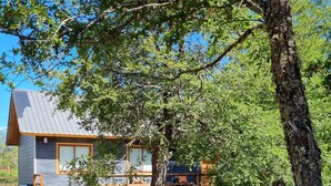 A cabin with a deck, surrounded by trees. - Refugios de Montaña Reloncaví - RL1 (Pinto)