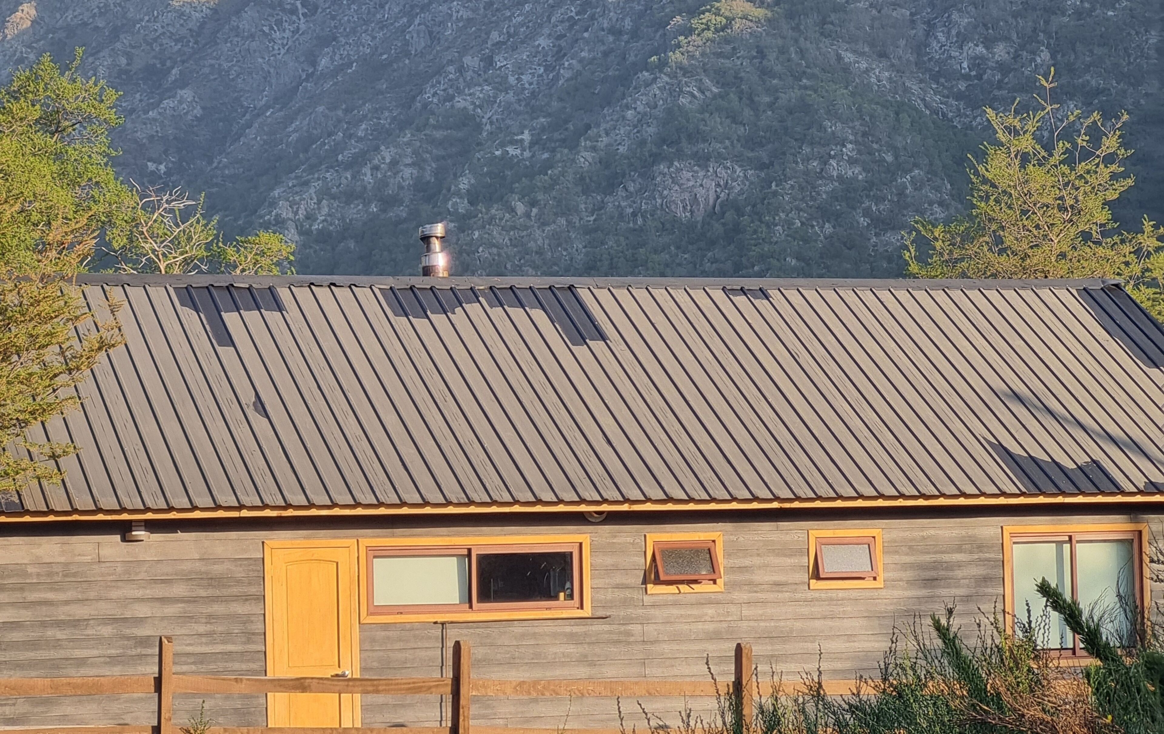 Une cabane avec un toit en métal, des murs en bois et une cheminée.