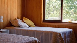 A room with two beds, a window, and a lamp. - Refugios de Montaña Reloncaví - RL1 (Pinto)