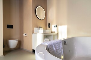 A modern bathroom with a freestanding bathtub, a toilet, and a vanity with a mirror.