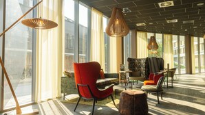 Un área de estar moderna con amplios ventanales, asientos cómodos e iluminación colgante elegante.