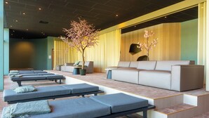 Un spa moderno con múltiples camillas de masaje, un sofá y plantas decorativas.
