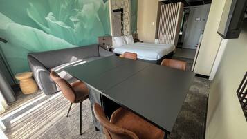Hotelkamer met een bed, een slaapbank, een eettafel met stoelen en een grote bloemenmuur.