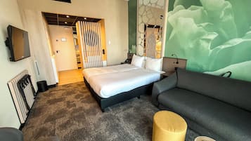 Una habitación de hotel con una cama, un sofá, una mesita y una pared con un diseño abstracto en verde.