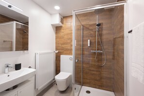 A modern bathroom with a glass-enclosed shower, a white sink, and a toilet. - Homaris Apartments München Laim (Munich)