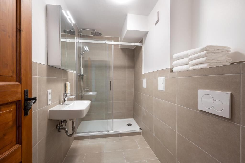 Un baño moderno con ducha acristalada, lavamanos y toallero.