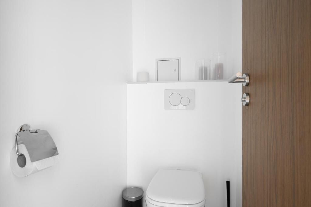 Ein schlichtes Badezimmer mit Toilette, Mülleimer und festmontiertem Toilettenpapierhalter.