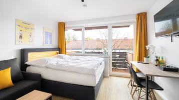 Una habitación de hotel con cama, sofá, escritorio y televisor.