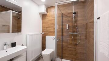 A modern bathroom with a glass-enclosed shower, a white sink, and a toilet.