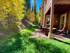 A patio with outdoor seating, a brick pathway, and a view of yellow foliage and trees. - Stylish Lodge with Pool/Hot Tub/Shuttle (Keystone)