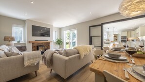 A modern living room with a fireplace, sofa, and dining area. - Larks Rise, Burnham Market, Norfolk (Burnham Market)