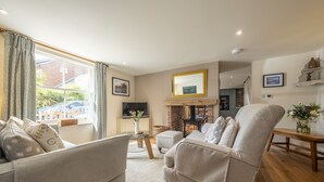Uma sala de estar com lareira, televisão e área de jantar com mesa e cadeiras de madeira.
